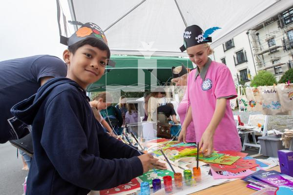 Picture by Karl Dorfner. 01-09-2024 - Havelet Regatta - Ethan Cali (8) at the arts and crafts area with volunteer Eliza Bratley helping out