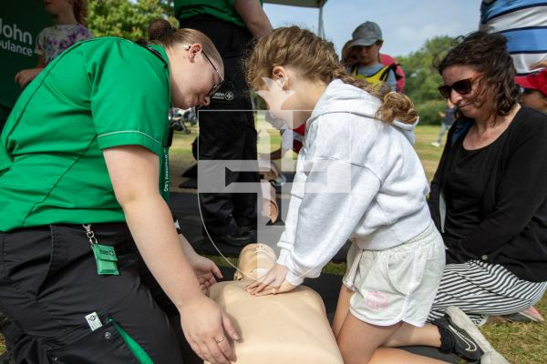 Picture by Karl Dorfner. 31-08-2024 - The Sauzmarez Park Sports Day Event - Millie macfarlane (9) with mum Jana and St Johns helper Kira Murphy, going over the various stages of CPR on a dummy