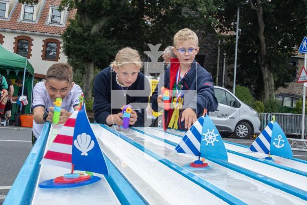 Picture by Karl Dorfner. 01-09-2024 - Havelet Regatta - Findlay Cussac (10) with brother and sister Wencke 'V' (12) and Frithjof 'V'  (10) playing the game where you have to propel boats forward using water pistols