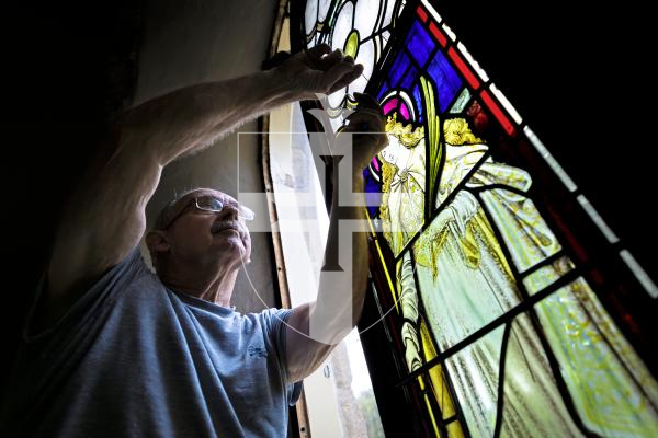 Picture by Peter Frankland. 27-08-25 A stained glass window at Forest Church has been removed, restored and is now being reinstalled in place. Peter Vivian of Guernsey Glass Craft was carrying out the work.