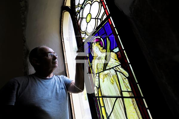 Picture by Peter Frankland. 27-08-25 A stained glass window at Forest Church has been removed, restored and is now being reinstalled in place. Peter Vivian of Guernsey Glass Craft was carrying out the work.