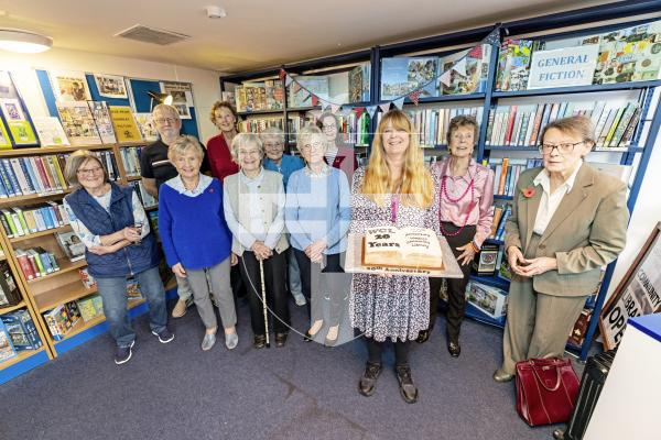 Picture by Sophie Rabey.  10-11-25.  The Western Community Library is celebrating 20 years with a party at St Saviour's Community Centre.
Users and volunteers of the Library at the community centre.
Jackie Burgess, Guille-Allès Library's Community and Wellbeing Lead, holds a celebration cake.