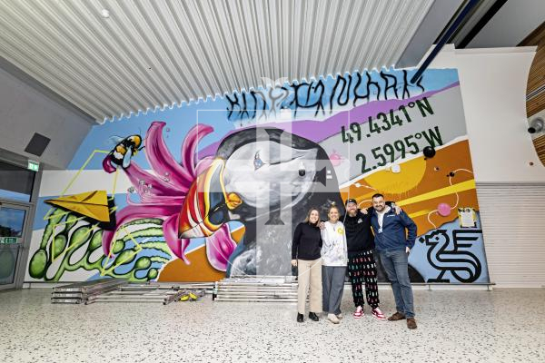 Picture by Sophie Rabey.  24-11-25.  The mural at Guernsey Airport, sponsored by Butterfield, has officially opened.  Tiffany Anna and Woodie have spent the last few weeks painting the scene of Guernsey related images.
L-R Claire Heaume (Marketing Manager at Butterfield), Tiffany Anna, Woodie and David Buddery (Guernsey Ports).