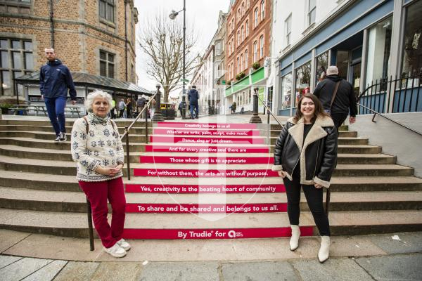 Picture by Sophie Rabey.  16-02-24.  A poem has appeared on the steps in Market Square celebrating the local creative community.  Local artist and poet Trudie Shannon (left)  created the poem in collaboration with Guernsey Arts.  Guernsey Arts partnership development executive, Louise Le Pelley, is pictured (right)