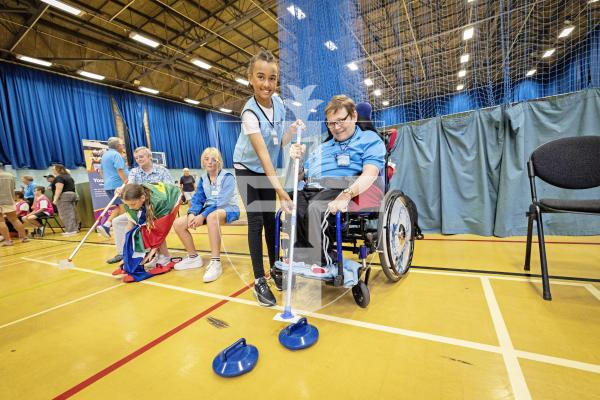 Picture by Sophie Rabey.  08-07-25.  A day of sports at Beau Sejour with students from St Martins Primary School and members of Guernsey Mobility, Lets Go!.  The children helped to assist those less able than them to compete in the challenges.
Olivia Elliot (aged 9) helping Lee Vaudin with a curling game.