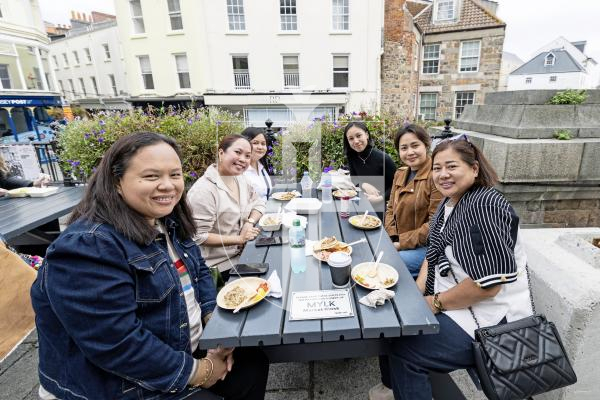 Picture by Sophie Rabey.  02-10-25.  'A Table in Guernsey' food festival at Market Square.  
L-R Evelyn Dile, Rachelle Angeles, Irene Navales, Trish Odulio, Althea David and Richell Hodgson enjoying a taste of home with Filipino Grilled Pork Sisig, cooked by Les Douvres.
