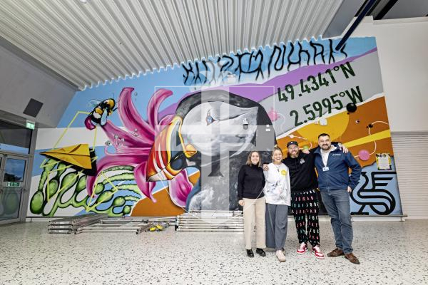 Picture by Sophie Rabey.  24-11-25.  The mural at Guernsey Airport, sponsored by Butterfield, has officially opened.  Tiffany Anna and Woodie have spent the last few weeks painting the scene of Guernsey related images.
L-R Claire Heaume (Marketing Manager at Butterfield), Tiffany Anna, Woodie and David Buddery (Guernsey Ports).