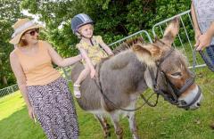 Pic supplied by Andrew Le Poidevin: 17-08-2024. The Guernsey Lions Club Donkey Derby at Saumarez Park. Nicola Penney offers support to her daughter Inara,3, as she completes a circuit riding a donkey.