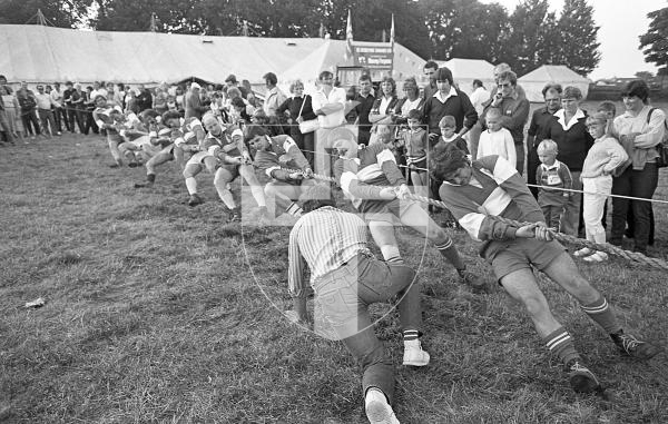 Picture by Guernsey Press. Nostalgia Lookback feature MONO. 
13th Aug 1983. Neg number 1577/7/83.
Coach John Le Tissier gets down to grass level to encourage the St Peter Port team in a heavyweight tug-of-war at the South Show.