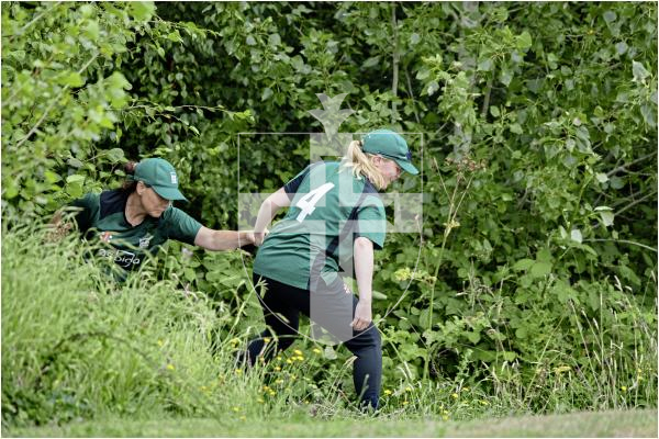 Guernsey's Eva Bourgaize helps Claire Davies out of the undergrowth after retreieving a lost ball